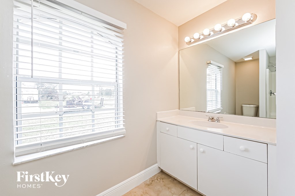 a bathroom with a large window and a sink and a mirror