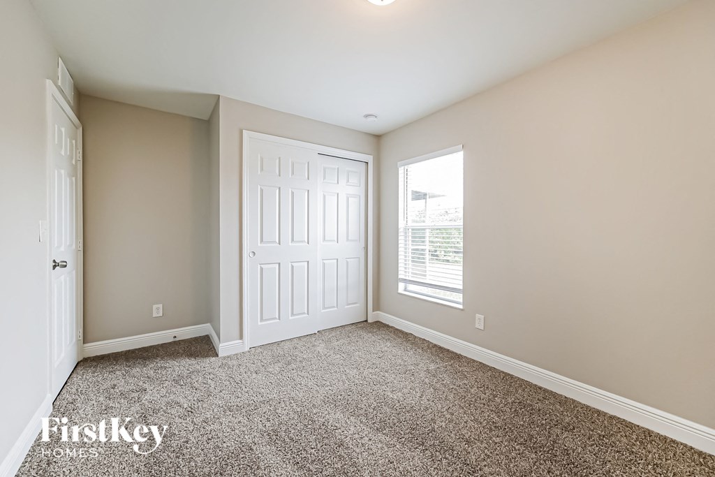 a bedroom with carpet and a white door and window