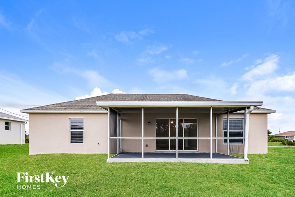 a beige house with a screened porch and a lawn