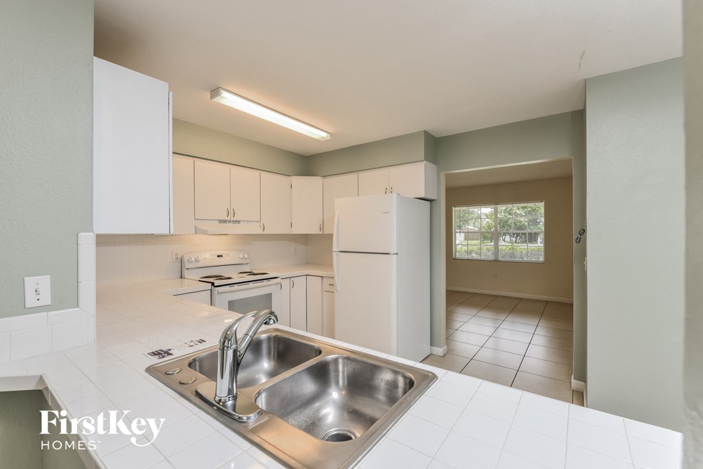 A kitchen with a stainless steel sink and white cabinets.