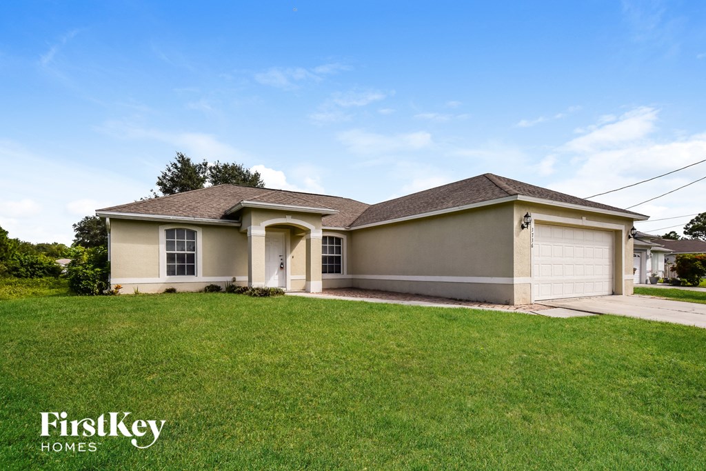 a beige house with a garage and a lawn
