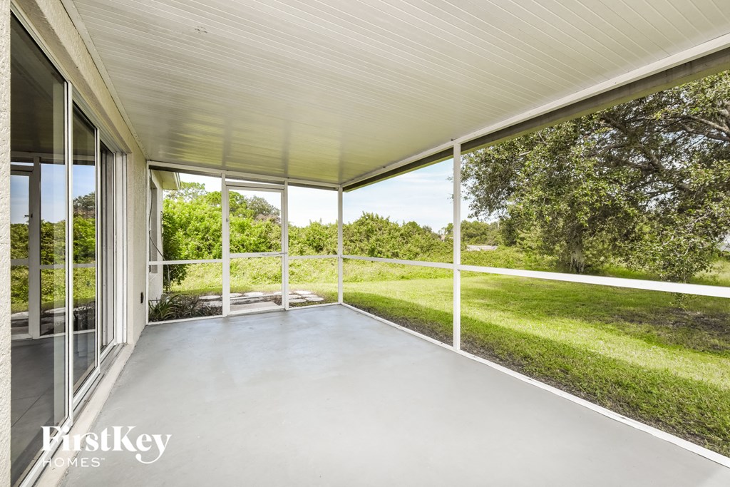 a covered porch with glass doors and a grass field