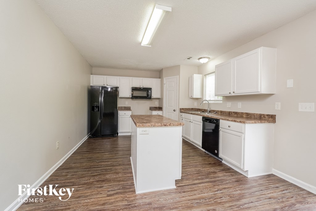 a kitchen with white cabinets and a black refrigerator