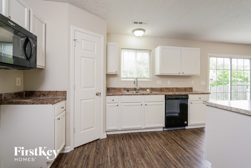 a kitchen with white cabinets and a black dishwasher and a sink