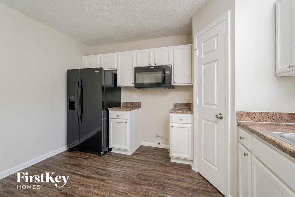 a kitchen with white cabinets and a black refrigerator