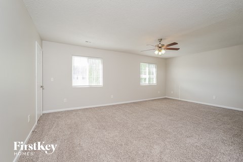 a spacious living room with carpet and a ceiling fan