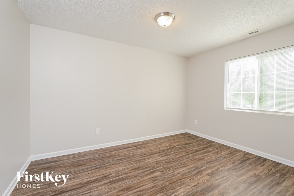 the spacious living room with wood flooring and a large window
