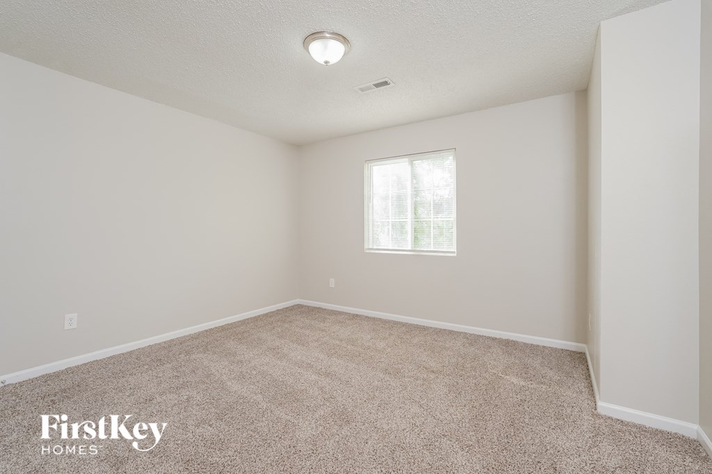 a spacious living room with carpet and a window