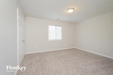 a spacious bedroom with carpet and a door to the bathroom