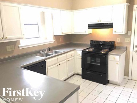 a kitchen with white cabinets and a black stove and a sink