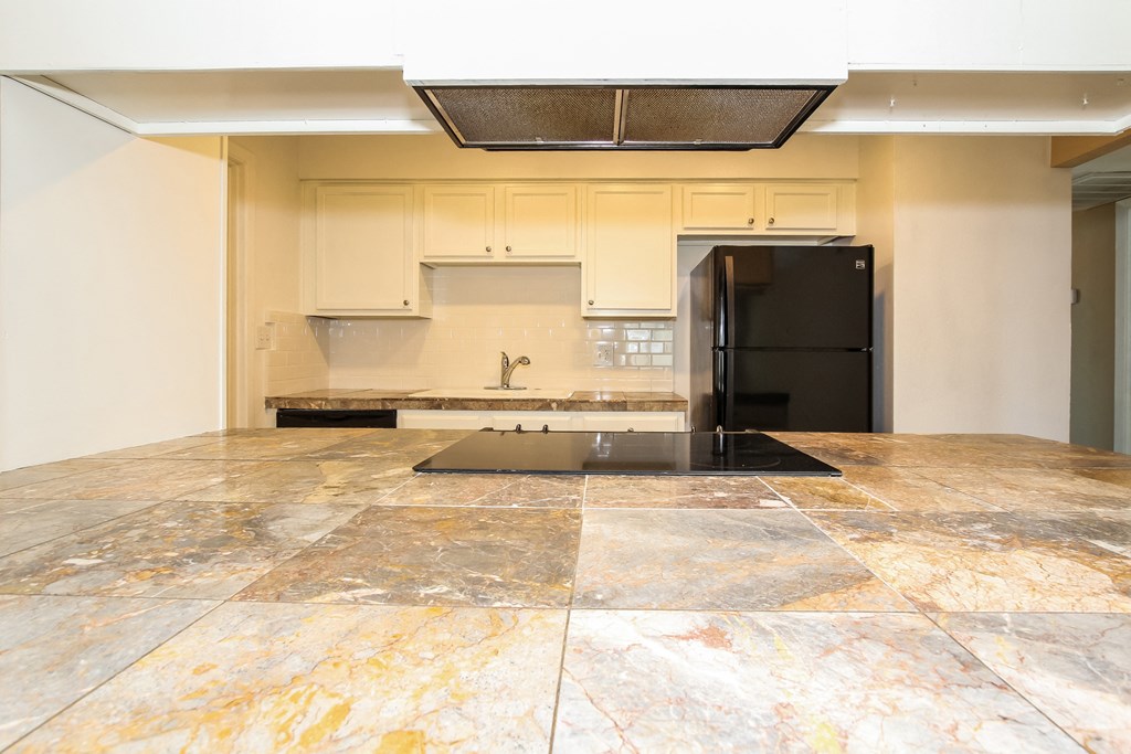 a kitchen with white cabinets and a black refrigerator