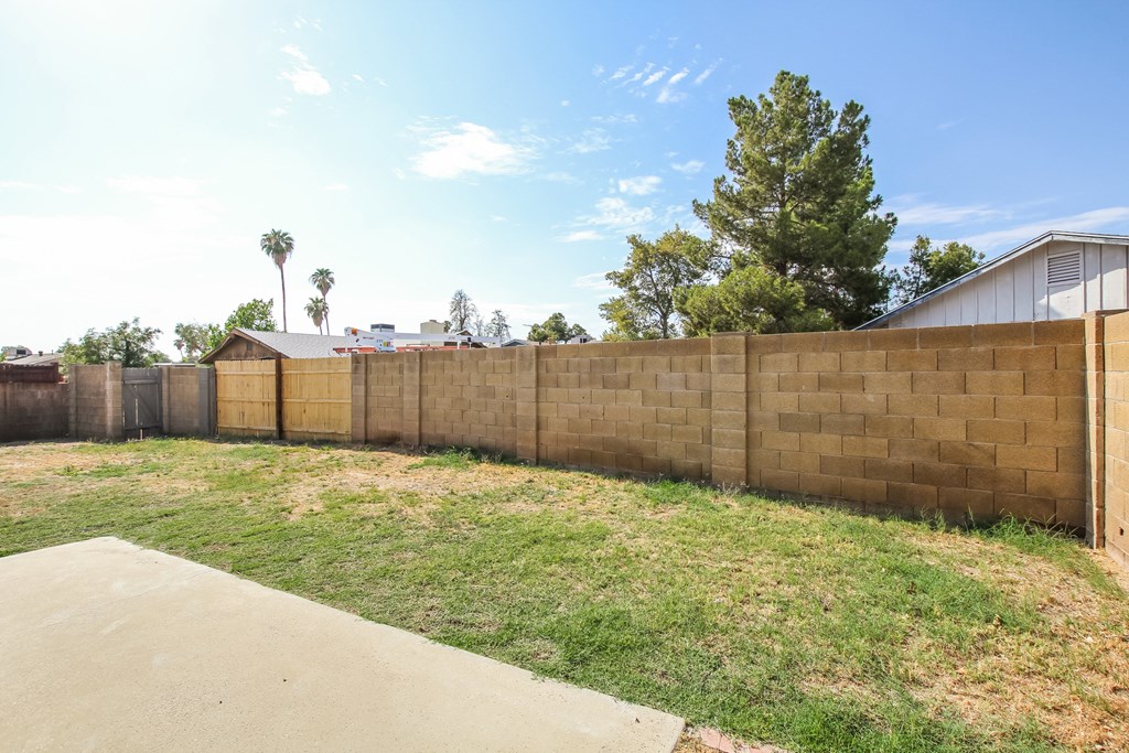 a retaining wall with a house behind it and a yard with grass
