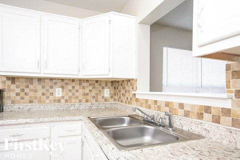 a white kitchen with white cabinets and a sink