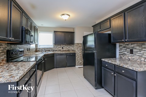 A kitchen with black cabinets and granite countertops.