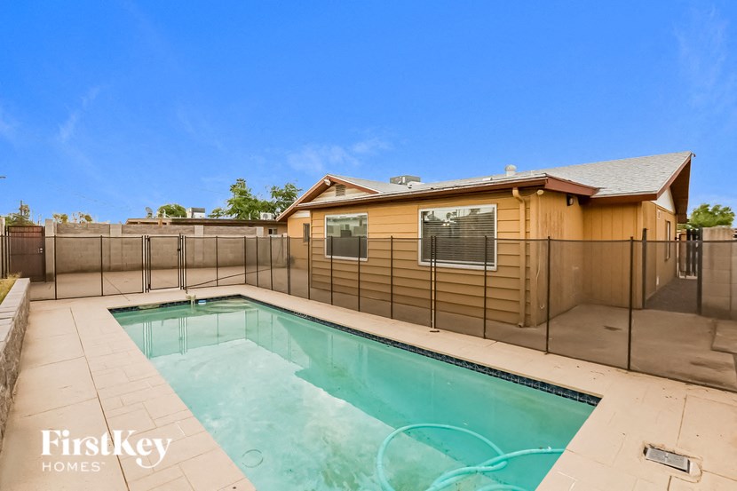 a backyard pool with a fence and a house
