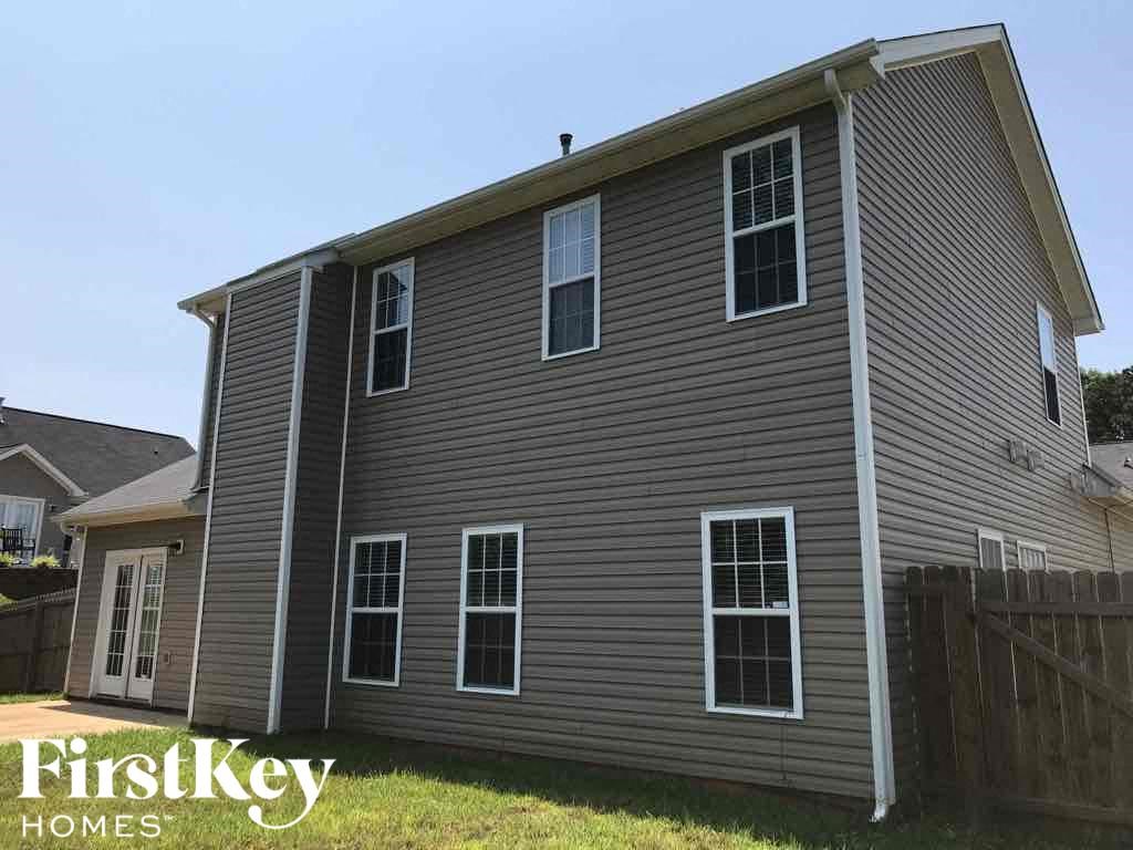 a gray house with white siding and a wooden fence