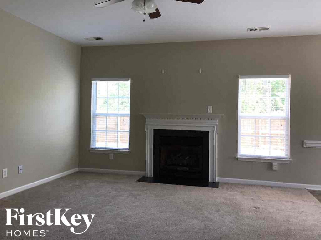 an empty living room with a fireplace and two windows