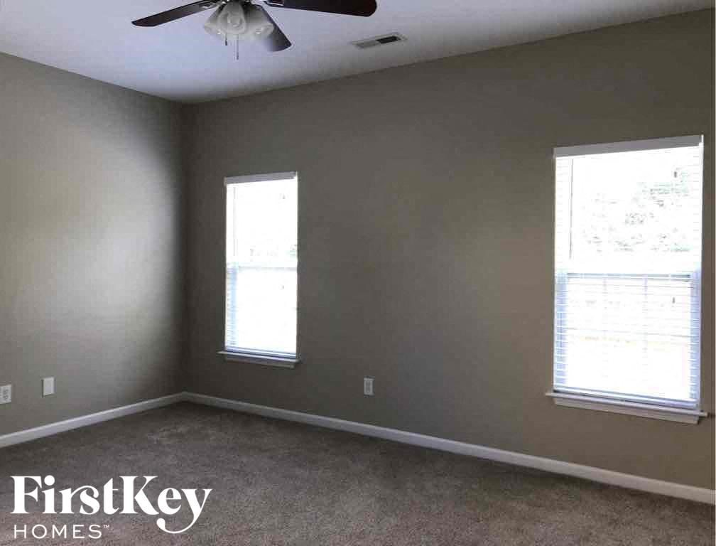 a gray room with two windows and a ceiling fan
