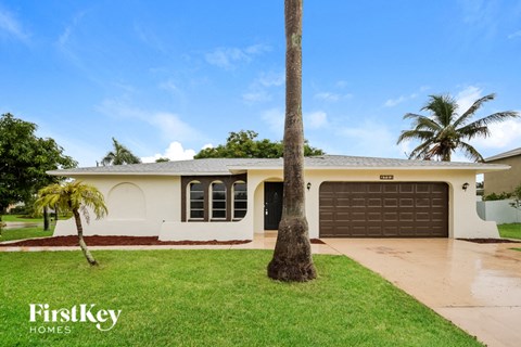 a home with a palm tree in the yard and a garage door