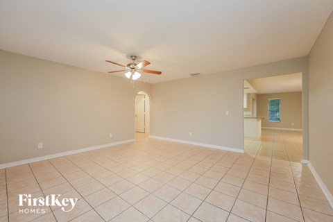 a empty living room with a ceiling fan and tiled floors