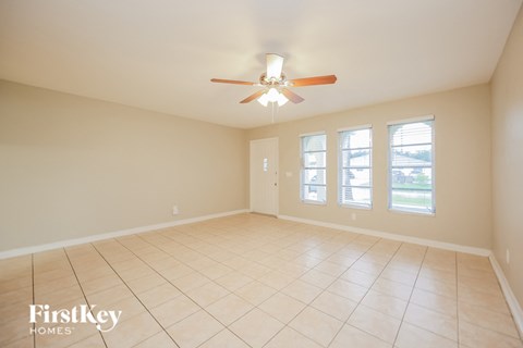 a empty living room with a ceiling fan and a tiled floor