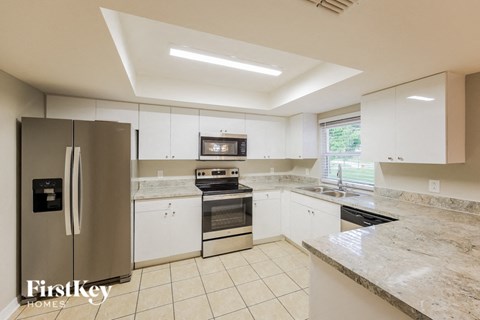 a large kitchen with white cabinets and stainless steel appliances