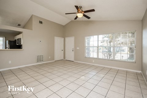 an empty living room with a ceiling fan and a window