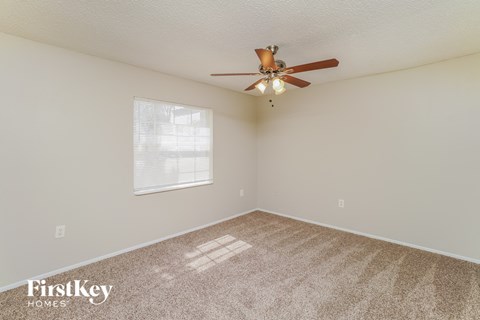 the spacious living room with ceiling fan and carpet