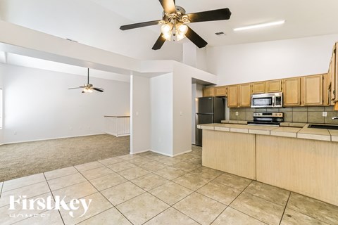 A spacious kitchen with a fan and a microwave on the counter.