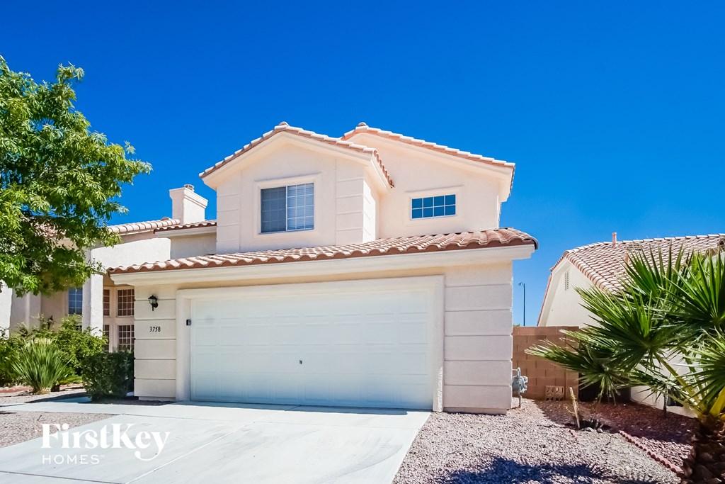 a white house with a garage door and a palm tree
