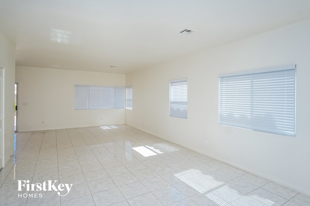 an empty living room with white walls and tile floors