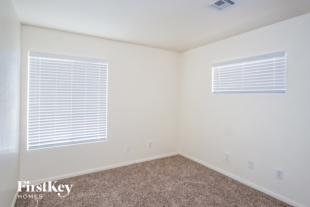 a bedroom with a carpeted floor and two windows
