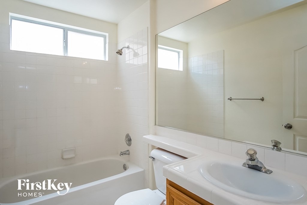 a white bathroom with a white sink and a tub and a white toilet