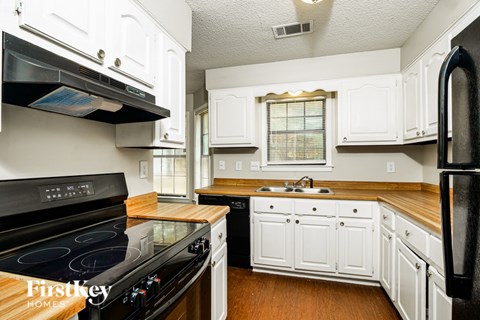 A kitchen with white cabinets and a black stove top oven.