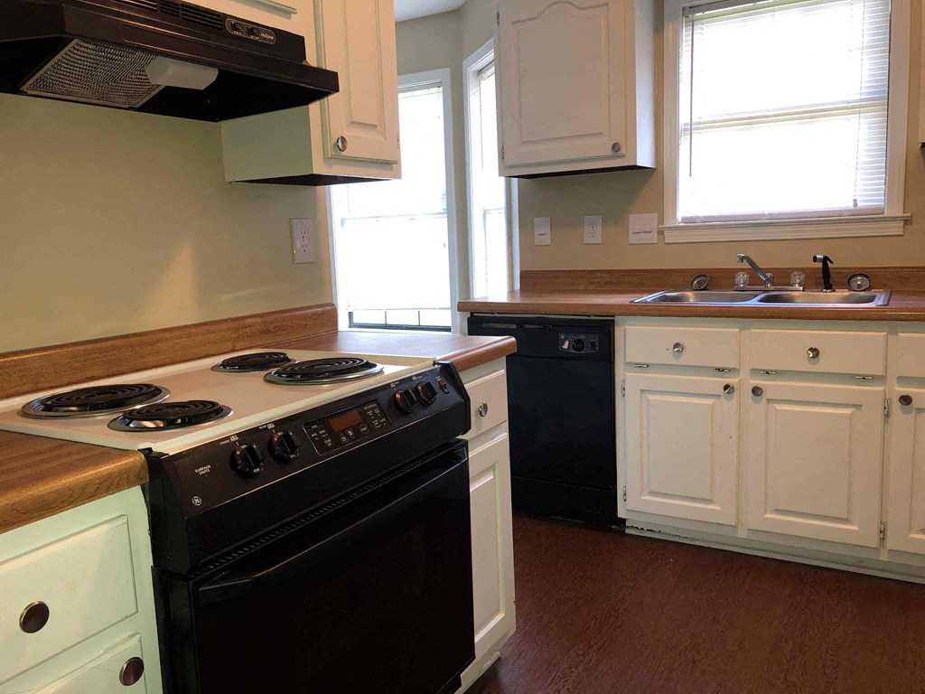 A kitchen with a black stove top oven and white cabinets.