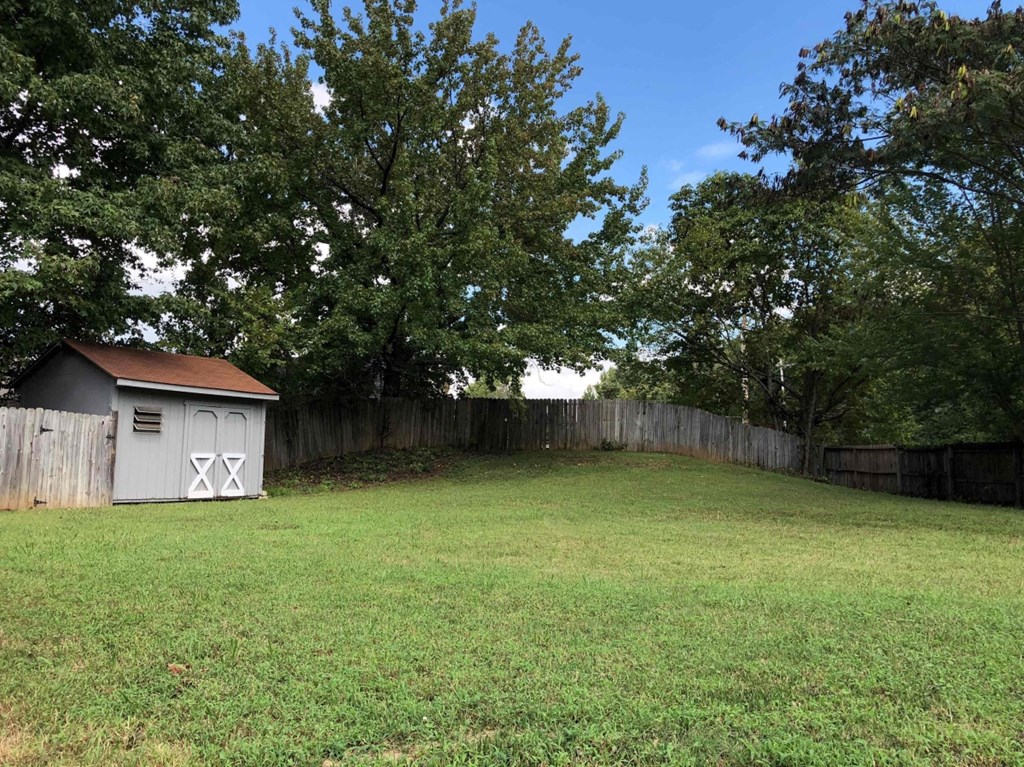 A small shed sits in a grassy backyard.