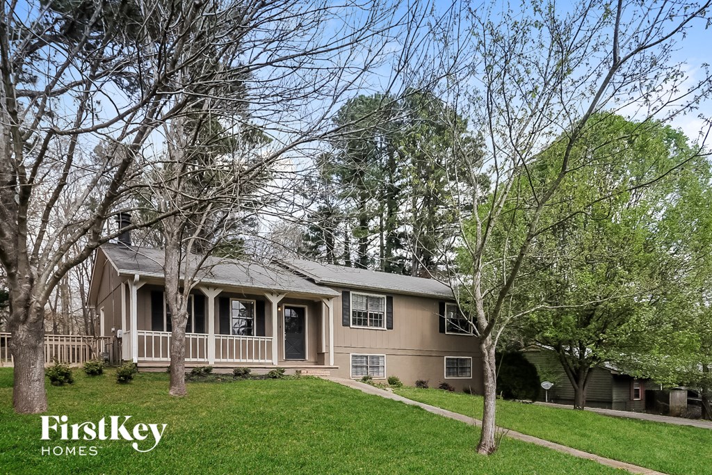 A house with a porch and trees in front of it.