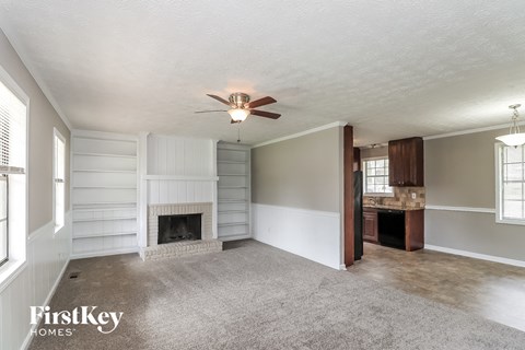 A spacious living room with a fireplace and a ceiling fan.