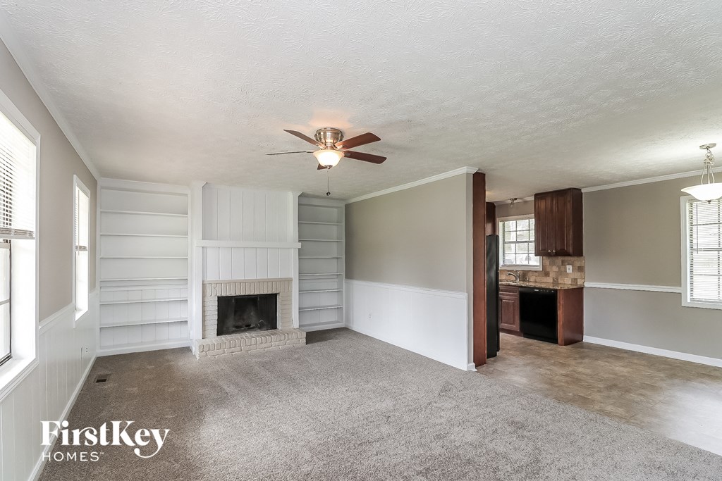 A spacious living room with a fireplace and a ceiling fan.