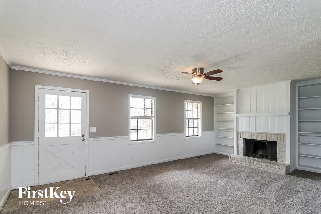 A spacious room with a fireplace and a ceiling fan.