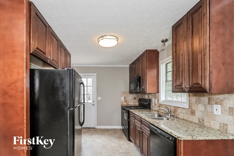 A kitchen with brown cabinets and a black fridge.