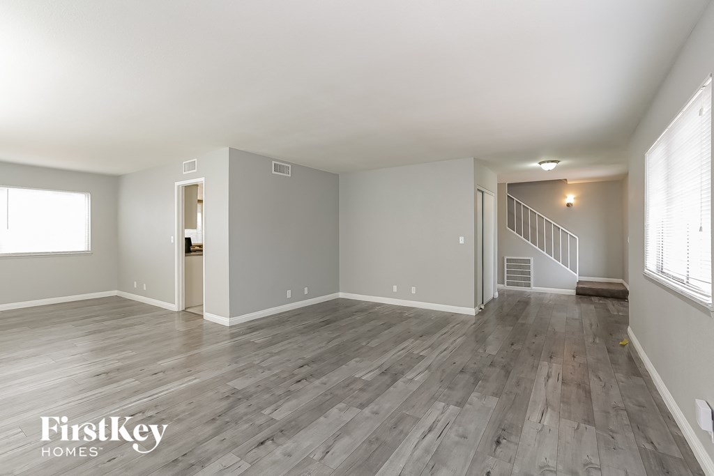 A spacious room with wooden flooring and white walls.