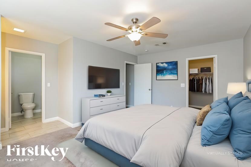 A bedroom with a bed, dresser, and a ceiling fan.