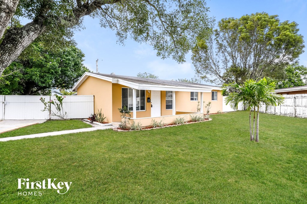 A house with a white fence and a tree in the front yard.