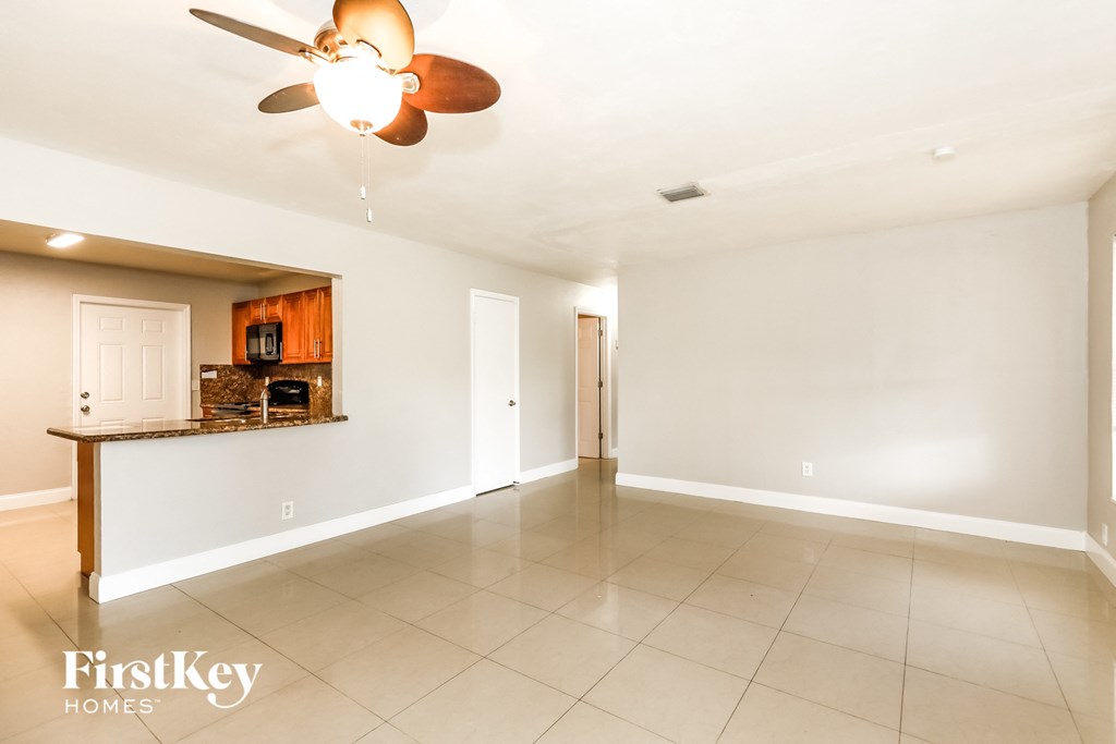 A spacious room with a ceiling fan and tiled flooring.