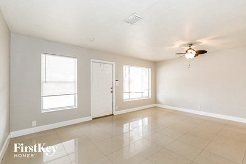 A spacious room with a ceiling fan and two windows.
