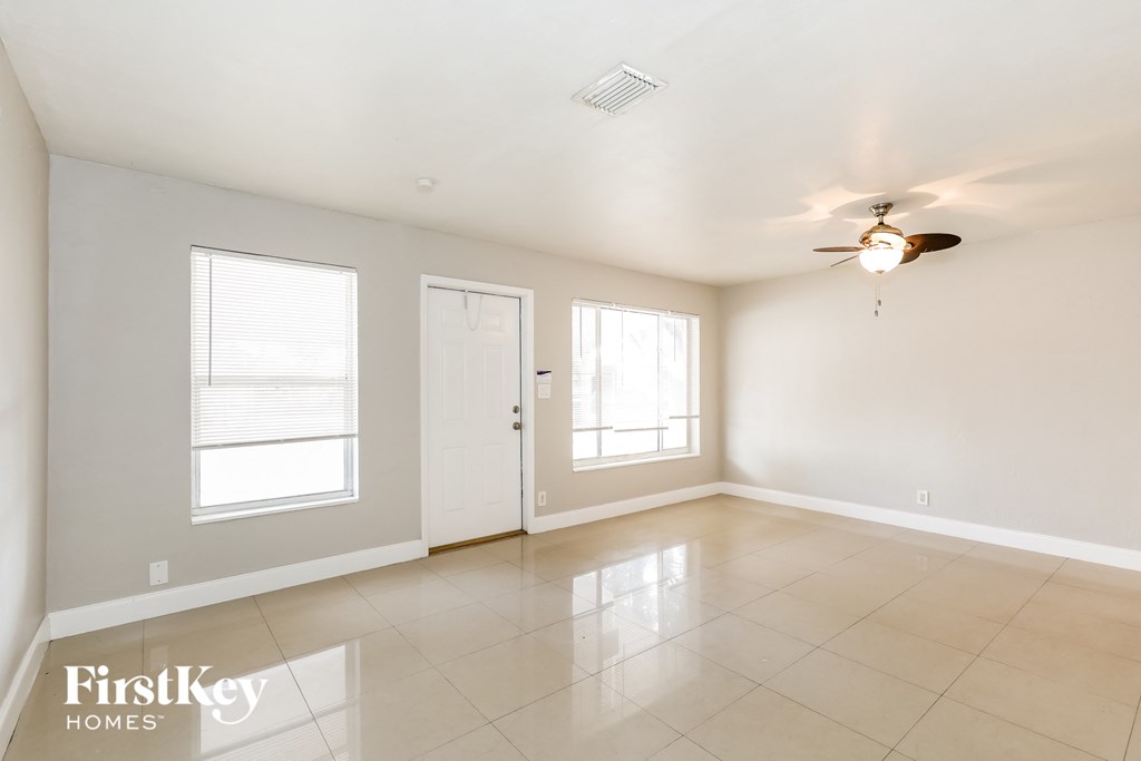 A spacious room with a ceiling fan and two windows.