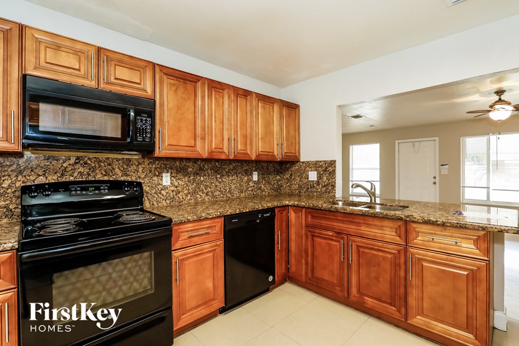 A kitchen with wooden cabinets and a black microwave.
