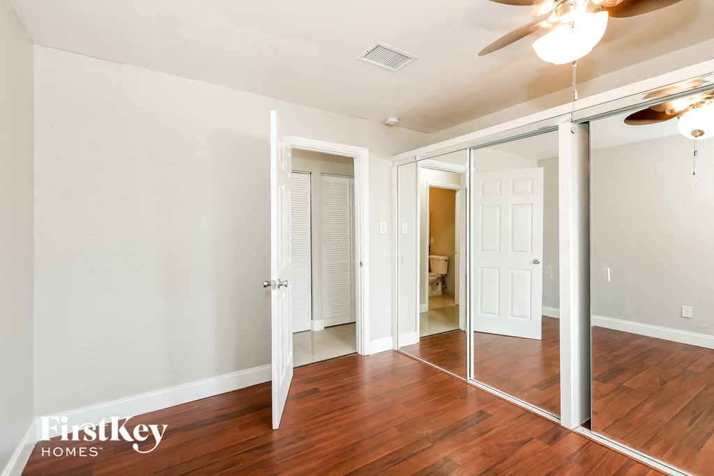 A room with a mirrored doorway and a ceiling fan.