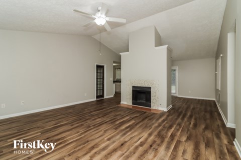 A spacious living room with wood flooring and a fireplace.